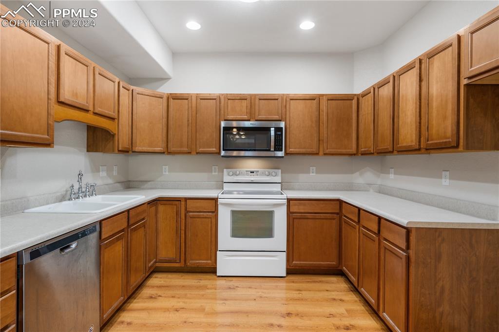 Image 8 of 30: Kitchen with appliances with stainless steel finishes, sink, and light hard