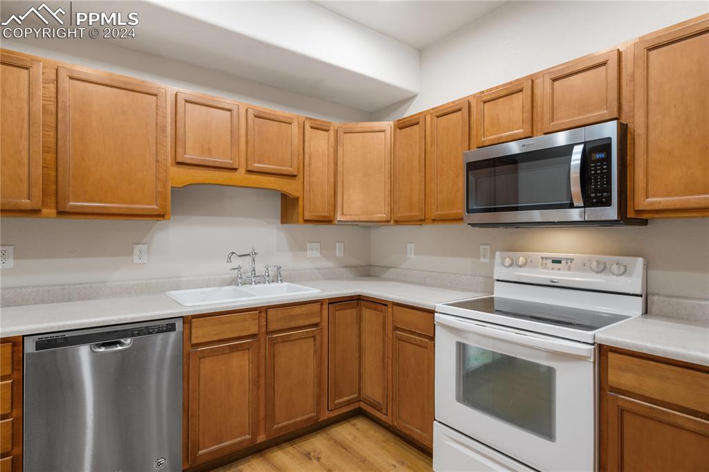 Image 9 of 30: Kitchen with appliances with stainless steel finishes, sink, and light wood
