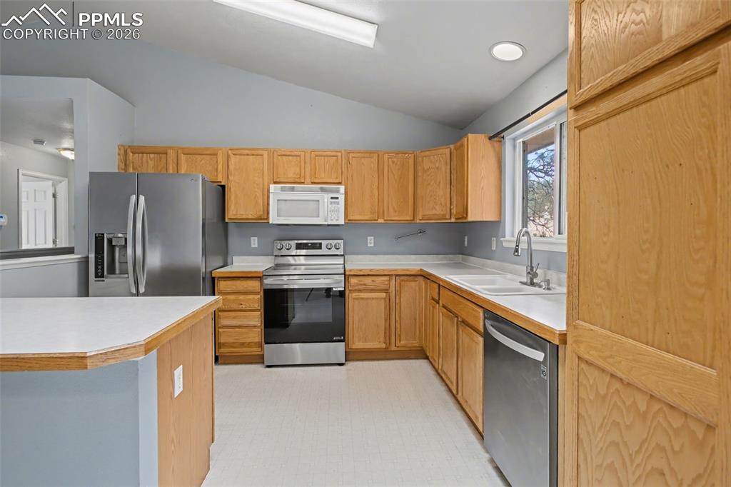 Image 10 of 49: Kitchen featuring light countertops, stainless steel appliances, lofted cei