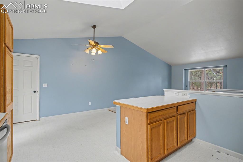 Image 12 of 49: Kitchen featuring wood finish cabinets, lofted ceiling, light countertops,