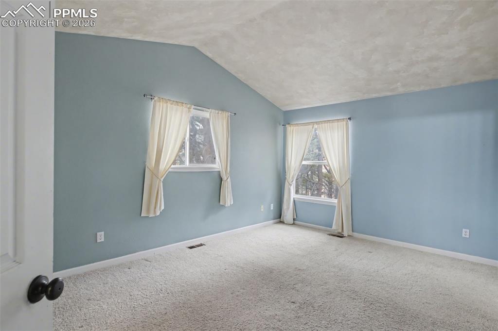 Image 13 of 49: Empty room with vaulted ceiling and carpet floors