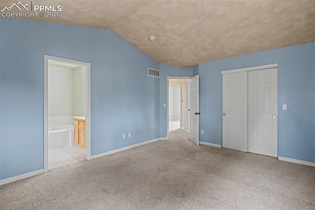 Image 15 of 49: Unfurnished bedroom featuring vaulted ceiling, a closet, light carpet, and