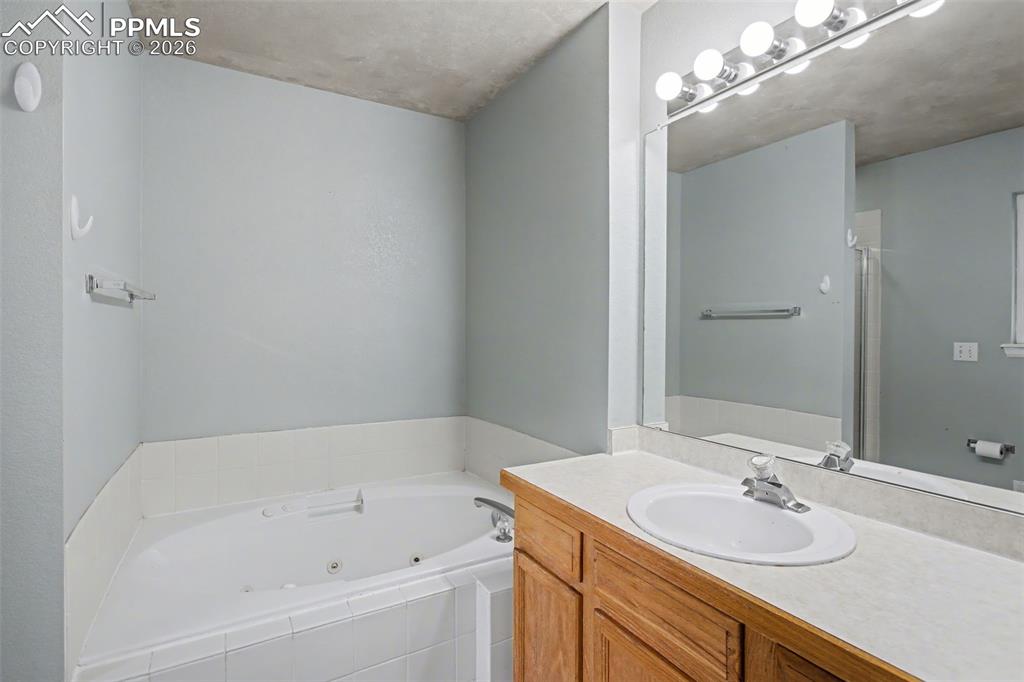 Image 16 of 49: Bathroom featuring a jetted tub and vanity
