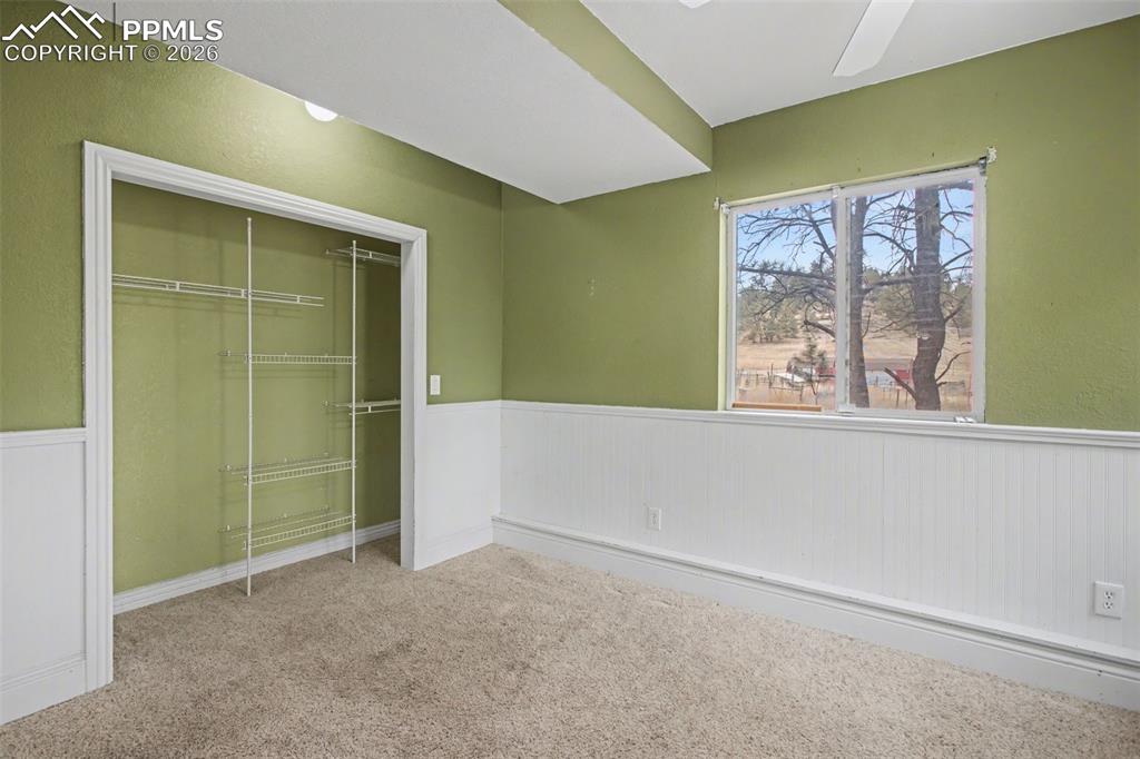 Image 24 of 49: Unfurnished bedroom with wainscoting, carpet flooring, a closet, and ceilin