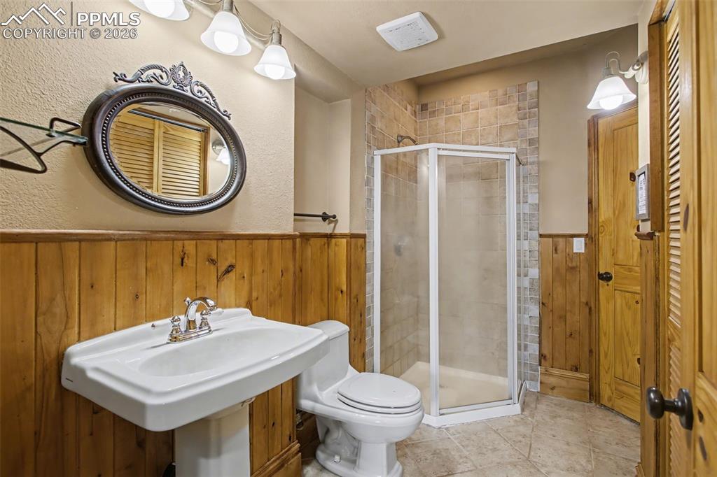 Image 25 of 49: Full bath featuring a stall shower, wood walls, a wainscoted wall, a textur