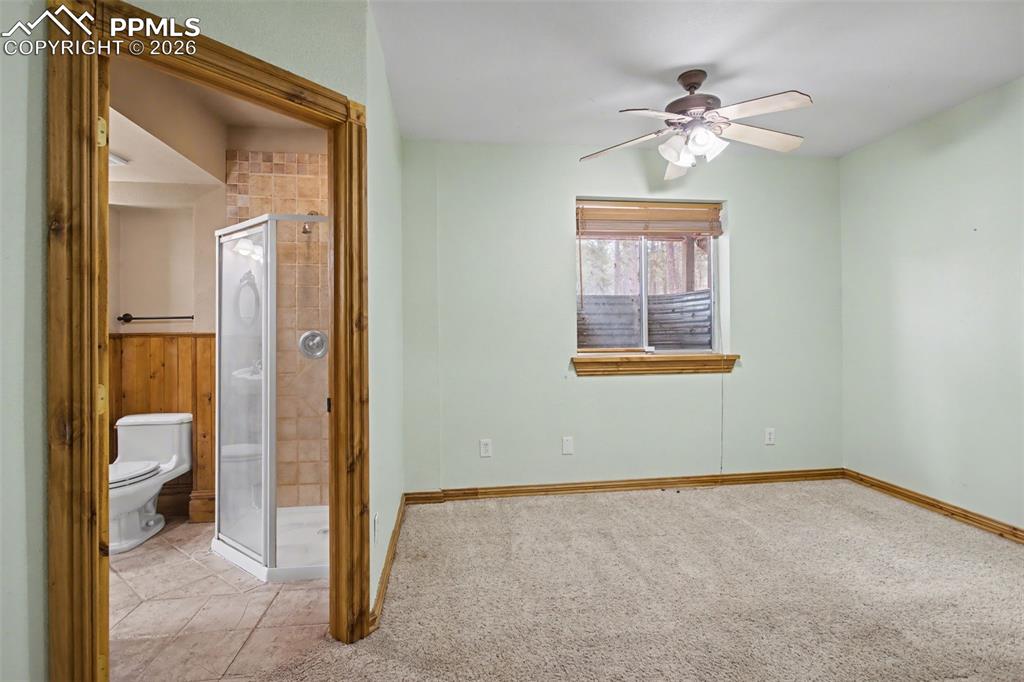 Image 30 of 49: Unfurnished bedroom with ensuite bathroom, a ceiling fan, and light carpet