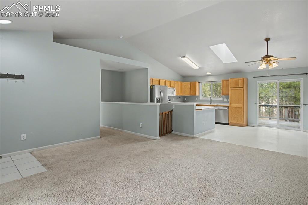 Image 7 of 49: Kitchen featuring open floor plan, a skylight, light colored carpet, a ceil