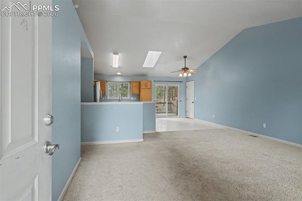 Image 9 of 49: Unfurnished living room with a skylight, light carpet, ceiling fan, and lof