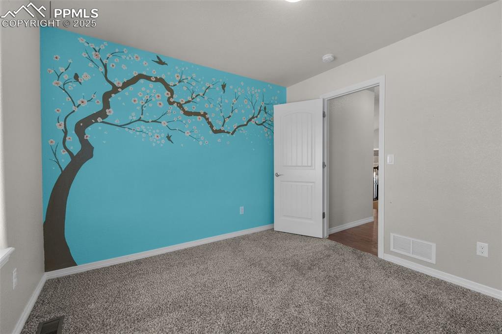 Image 18 of 38: Secondary main level bedroom #2 with accent wall