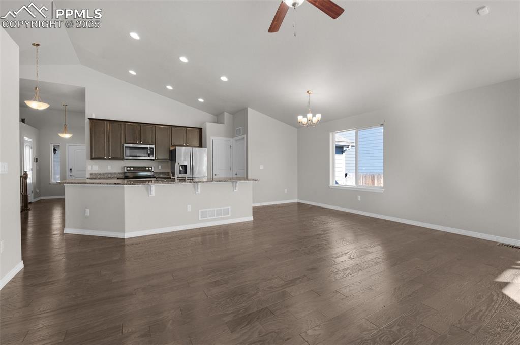 Image 6 of 38: Kitchen with open floor plan, light stone countertops, dark brown cabinets,