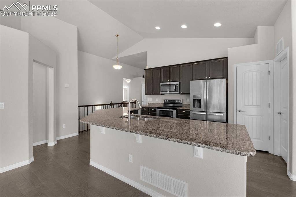 Image 8 of 38: Kitchen with stainless steel appliances, stone counters, dark wood finished