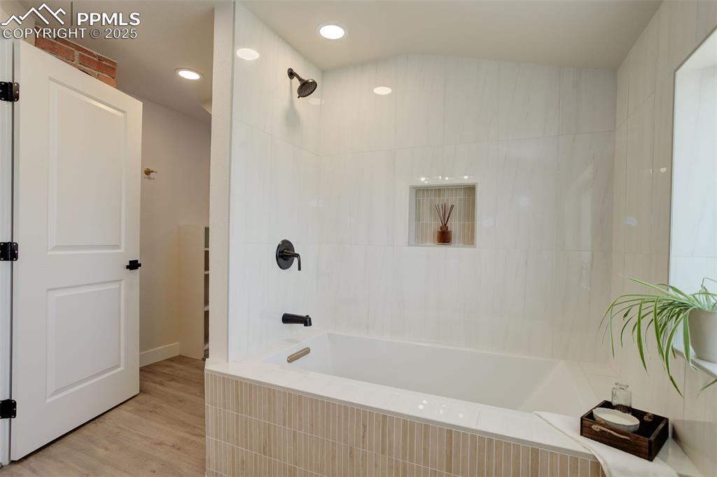Image 30 of 50: Primary bathroom with recessed lighting, shower combination, and wood fini