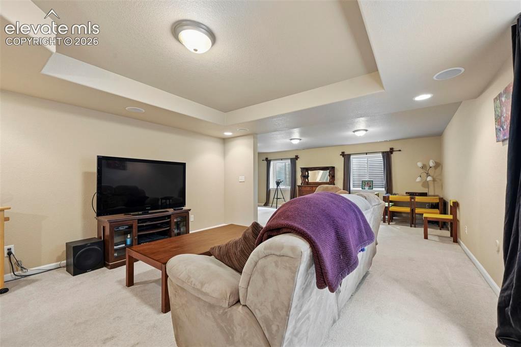 Image 10 of 32: Carpeted living area featuring recessed lighting, a tray ceiling, and neutr