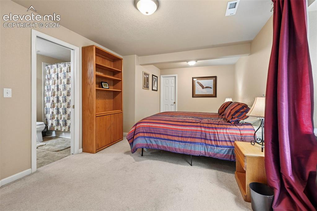 Image 16 of 32: Carpeted room with a built-in bookcase featuring open shelving and lower ca