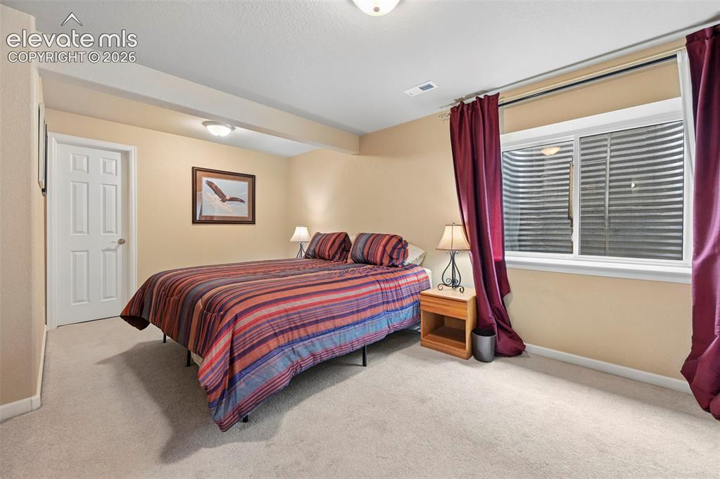 Image 17 of 32: Carpeted room featuring a white paneled door and a window with a corrugated