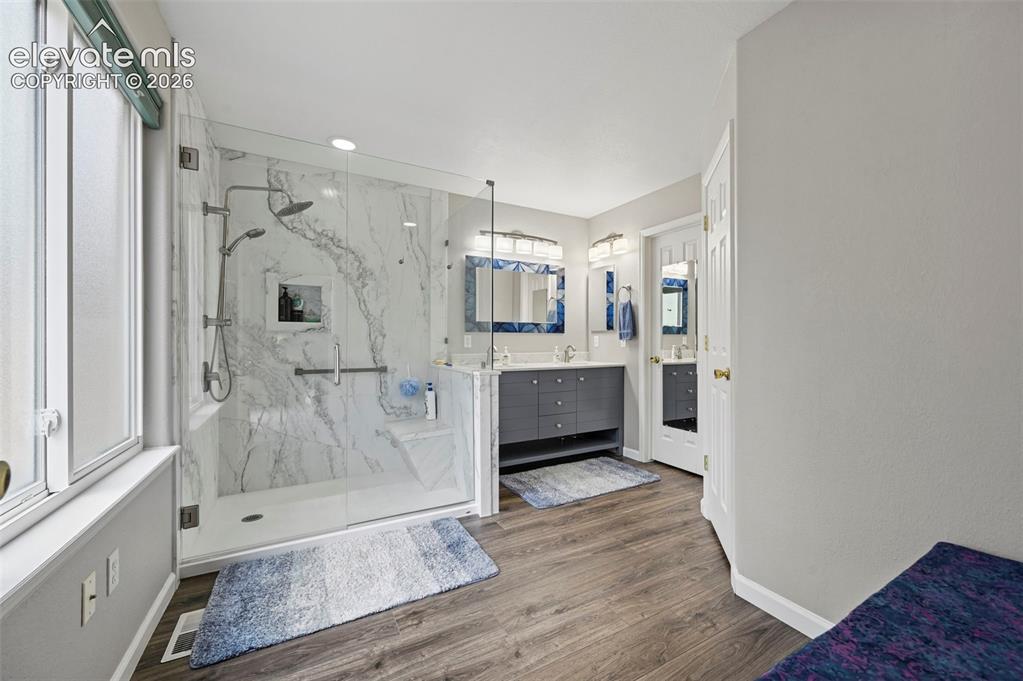 Image 23 of 32: Spacious bathroom featuring a glass-enclosed shower with white marble-style