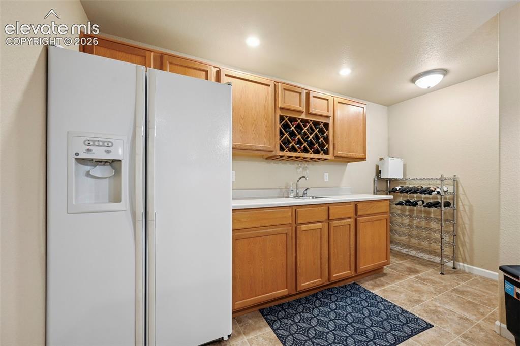 Image 24 of 32: Wet bar featuring wood cabinetry, integrated wine rack, countertop, and sin