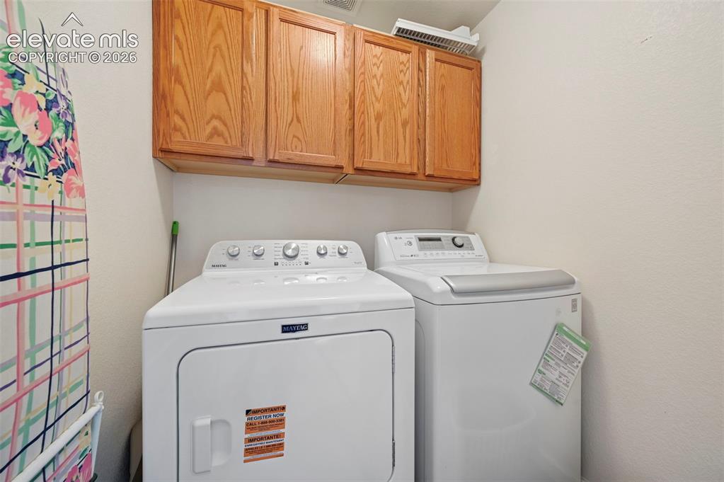 Image 26 of 32: Dedicated laundry area featuring overhead wood cabinetry