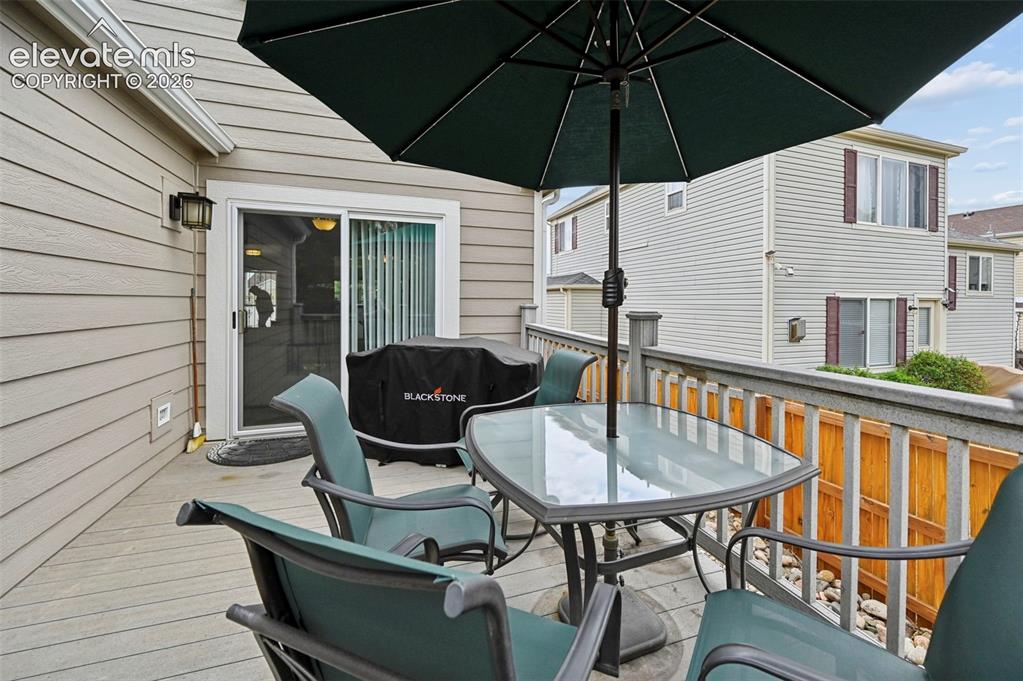Image 31 of 32: Outdoor deck featuring a glass-top table, sliding glass door, privacy raili