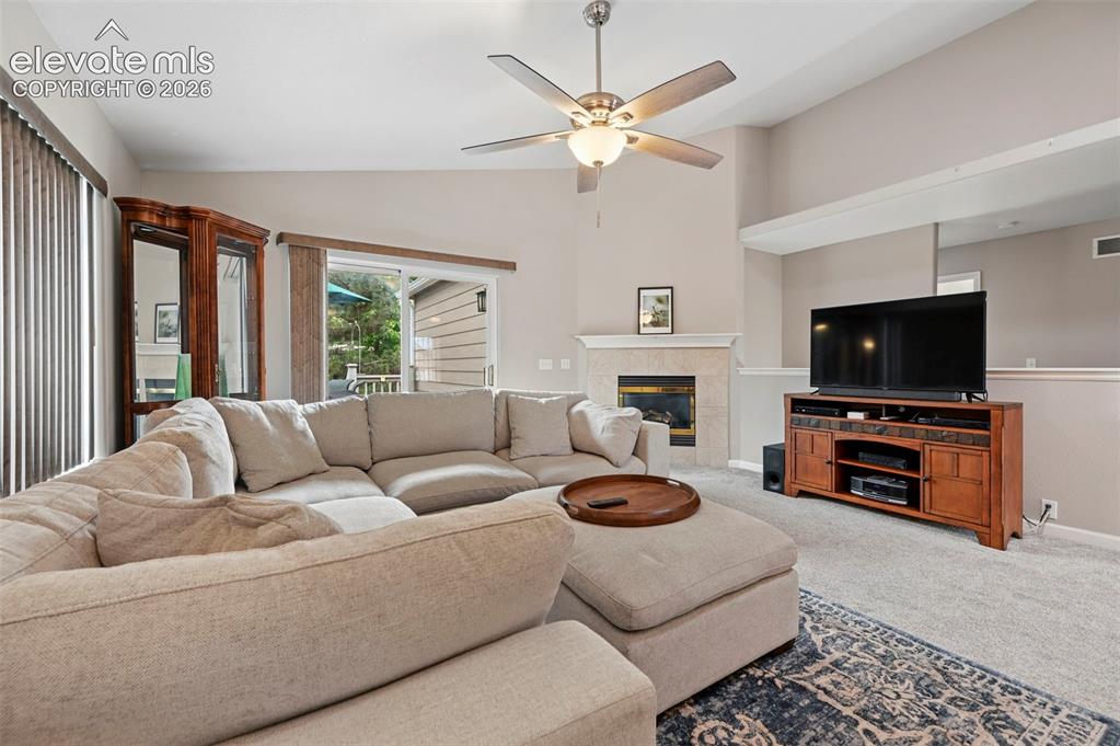 Image 4 of 32: Living area featuring a vaulted ceiling with a ceiling fan, a fireplace wit