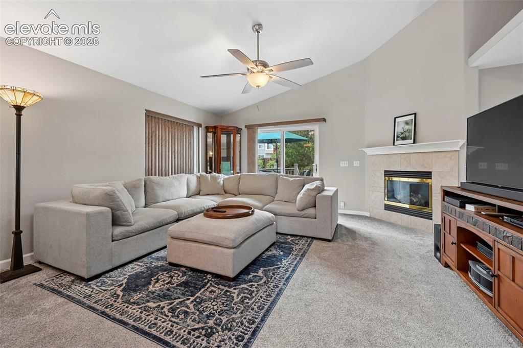 Image 5 of 33: Vaulted ceiling living space featuring a tiled fireplace with a mantel, a c