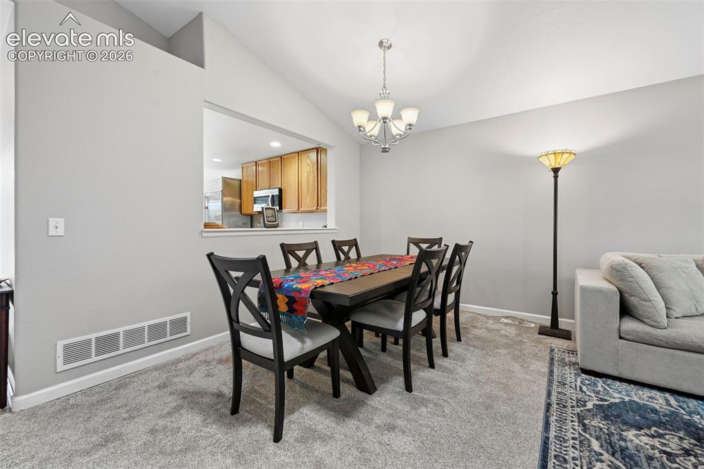 Image 8 of 32: Dining area featuring vaulted ceilings, a pass-through window to the kitche