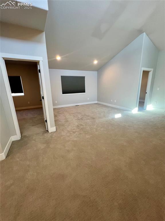 Image 12 of 19: Additional living space featuring vaulted ceiling, light carpet, and recess