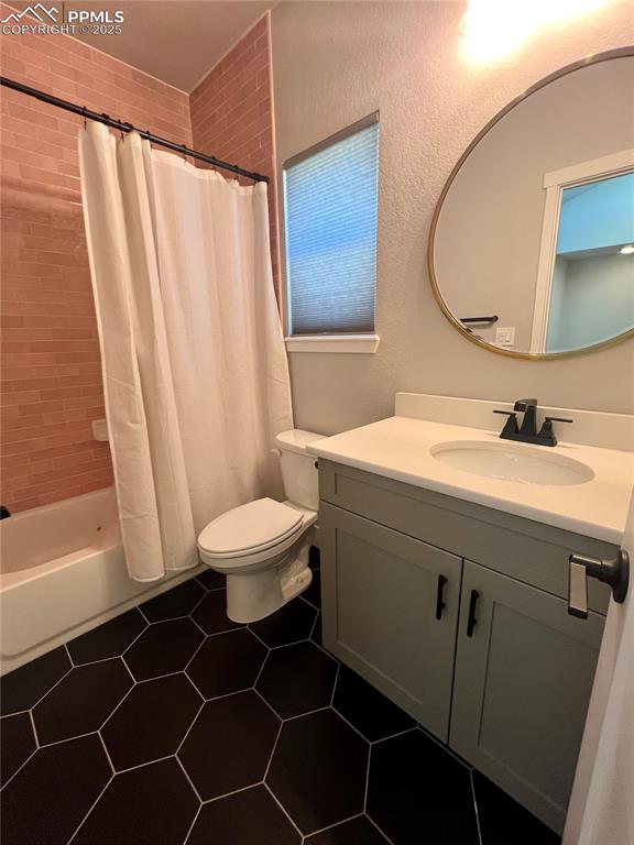 Image 14 of 19: Full bathroom featuring vanity, shower / bath combo, a textured wall, and d