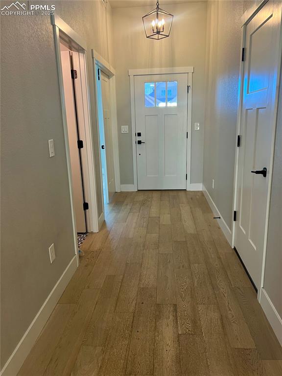 Image 18 of 19: Doorway featuring hardwood / wood-style flooring, a chandelier, and a textu