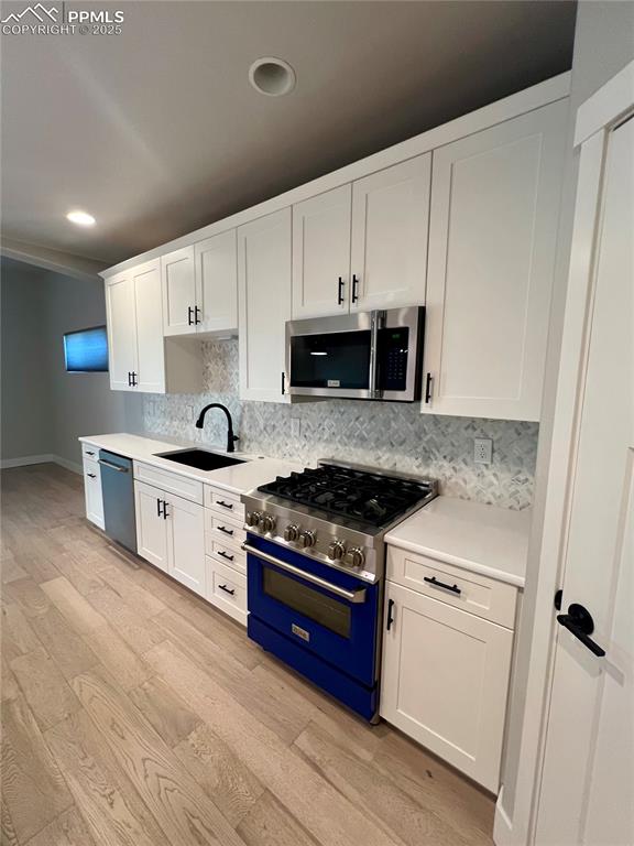Image 4 of 19: Kitchen with white cabinets, appliances with stainless steel finishes, ligh