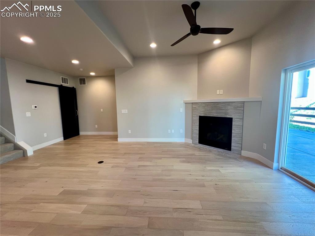 Image 5 of 19: Unfurnished living room featuring a barn door, light wood-style floors, rec