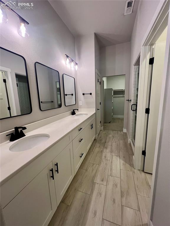 Image 7 of 19: Full bathroom featuring a spacious closet, double vanity, a stall shower, a