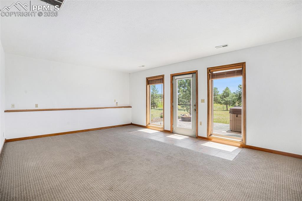 Image 31 of 49: Walk out basement door leads stamped concrete patio and hot tub