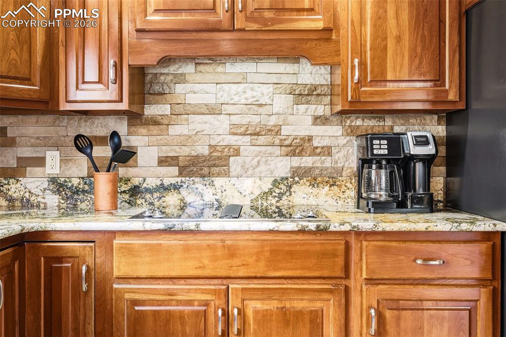 Image 15 of 50: Granite countertops and a stone tile backsplash complement the warm wood ca