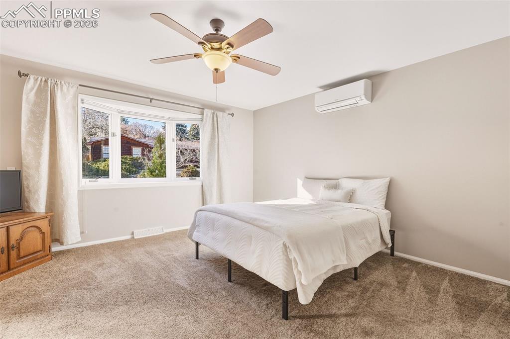 Image 18 of 50: Spacious main-level retreat with carpet, large picture window, ceiling fan,