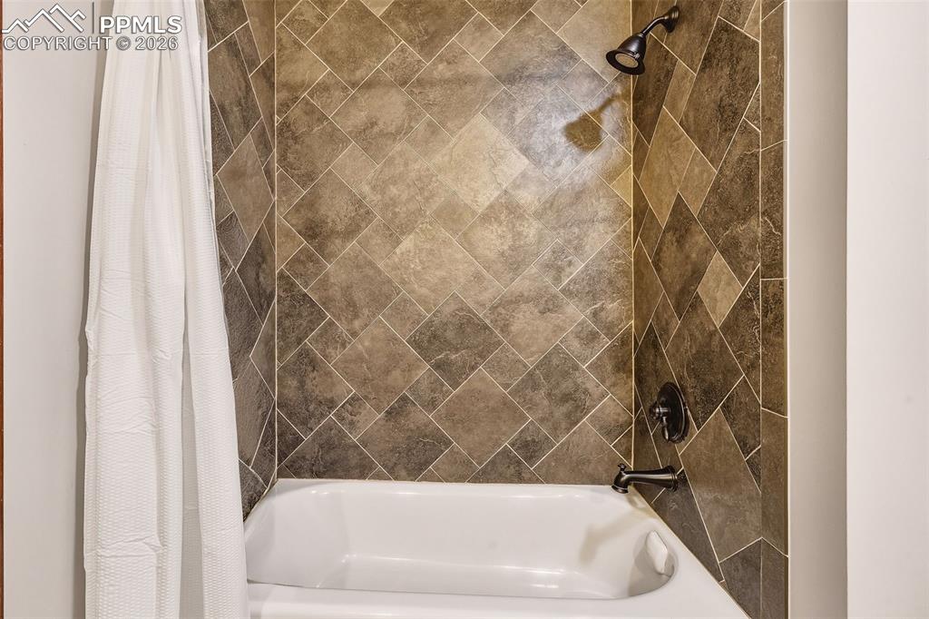 Image 25 of 50: Updated bath #2 featuring tile-surround tub/shower combination with modern