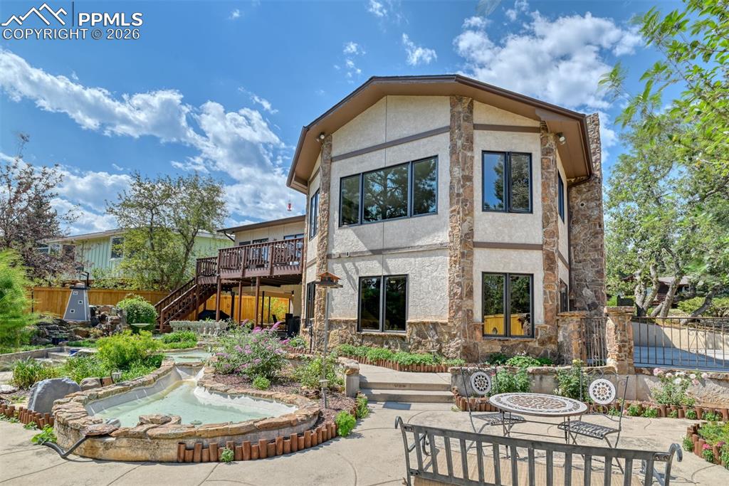 Image 39 of 50: Beautifully landscaped yard with winding walkways, water features, and matu