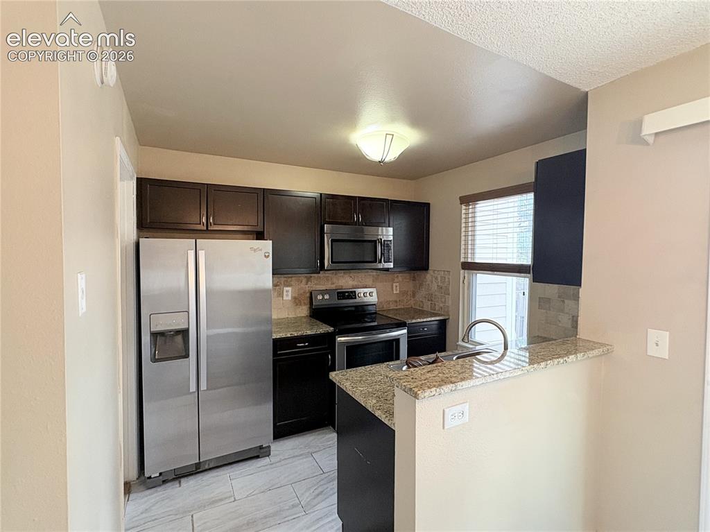 Image 13 of 31: The Kitchen boasts wood cabinets with granite countertops and tiled backspl