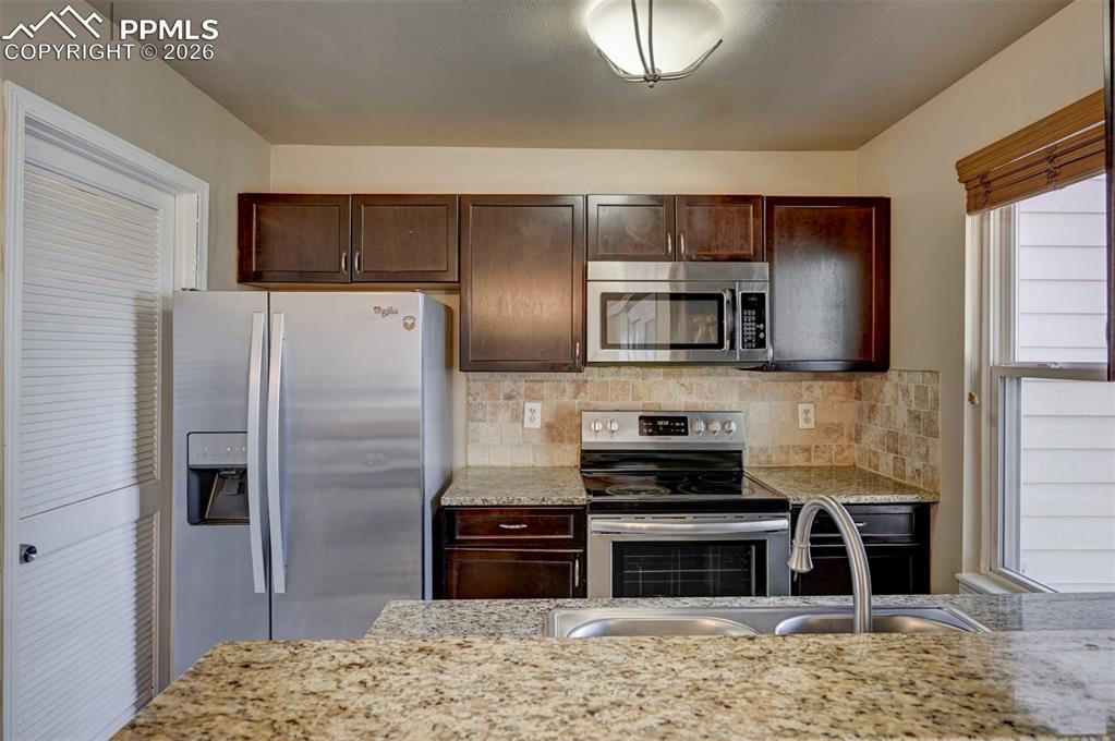 Image 15 of 31: The Kitchen boasts wood cabinets with granite countertops and tiled backspl