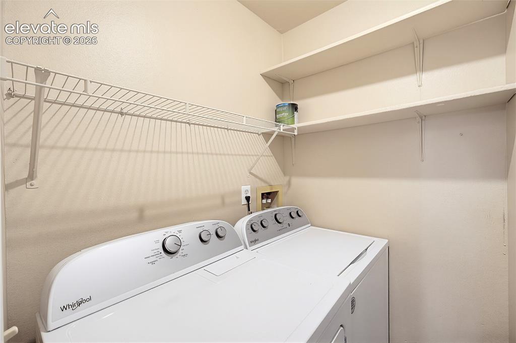 Image 15 of 31: The Laundry Room features built-in shelves and a washer and dryer.