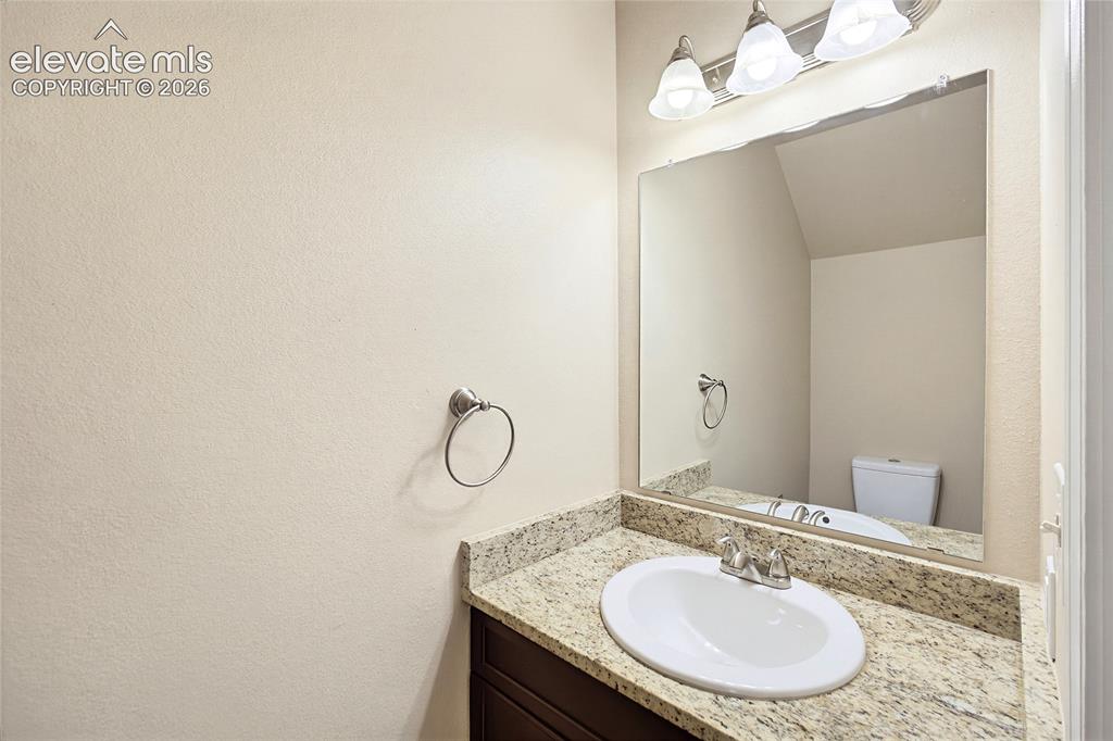 Image 5 of 31: Main Level Powder Bathroom with vanity and mirror.