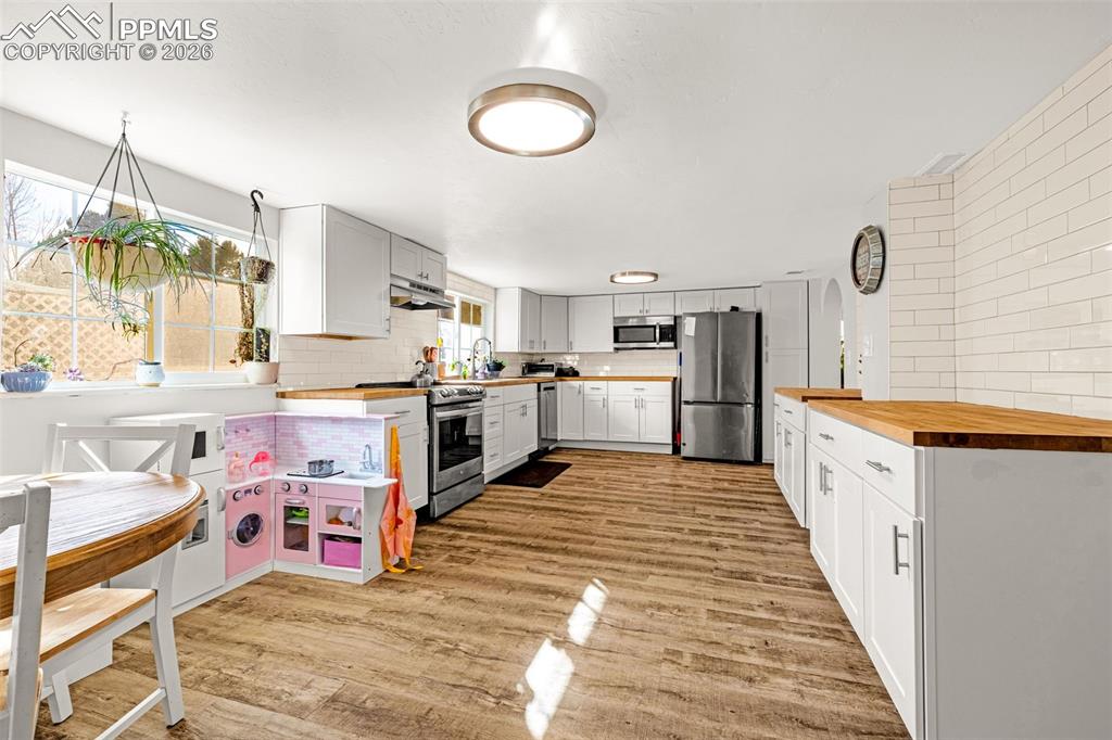 Image 11 of 38: Kitchen featuring wooden counters, backsplash, stainless steel appliances, 