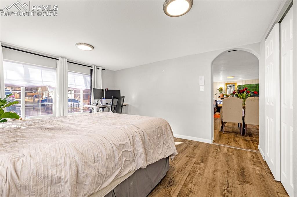 Image 14 of 38: Bedroom featuring arched walkways, dark wood finished floors, and a closet