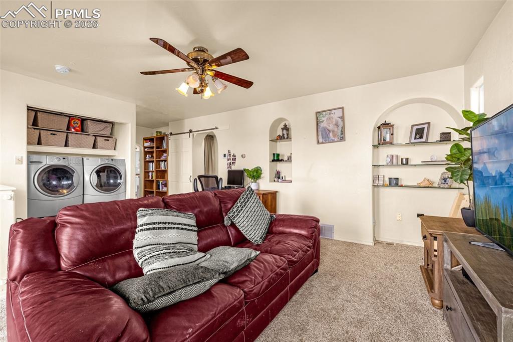 Image 19 of 38: Carpeted living room with ceiling fan, washing machine and clothes dryer, a