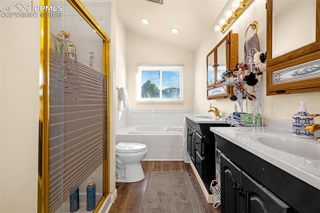 Image 22 of 38: Bathroom featuring vaulted ceiling, dark wood-type flooring, two vanities, 