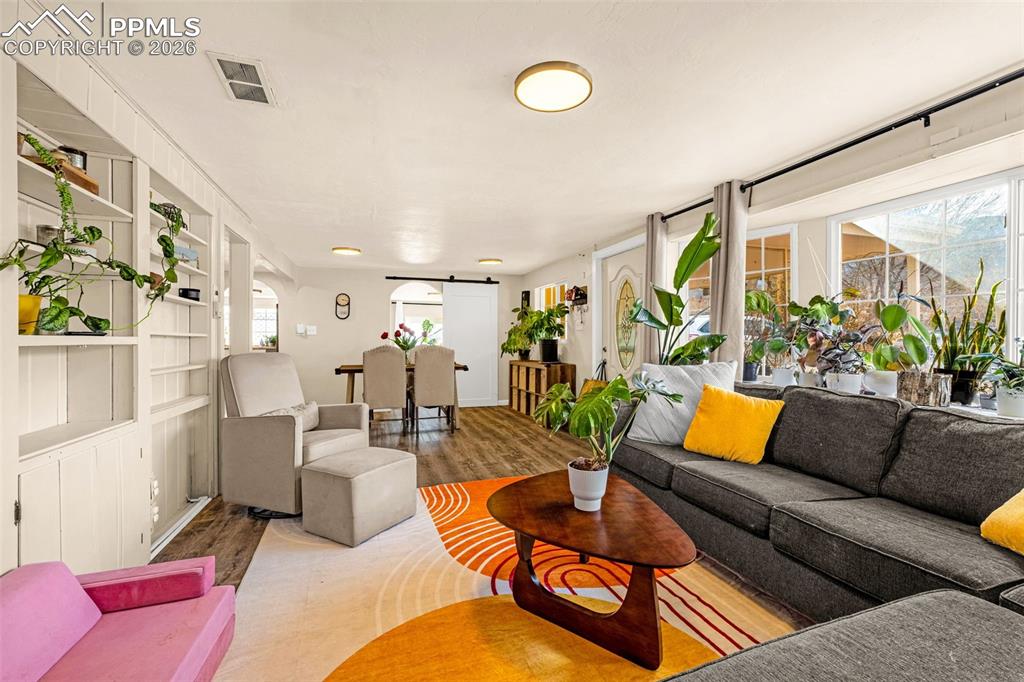 Image 5 of 38: Living area with wood finished floors, a barn door, and built in shelves