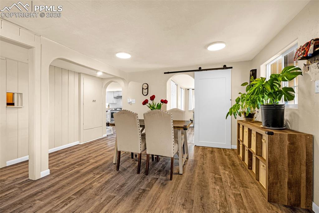 Image 6 of 38: Dining area with arched walkways, dark wood-style floors, plenty of natural