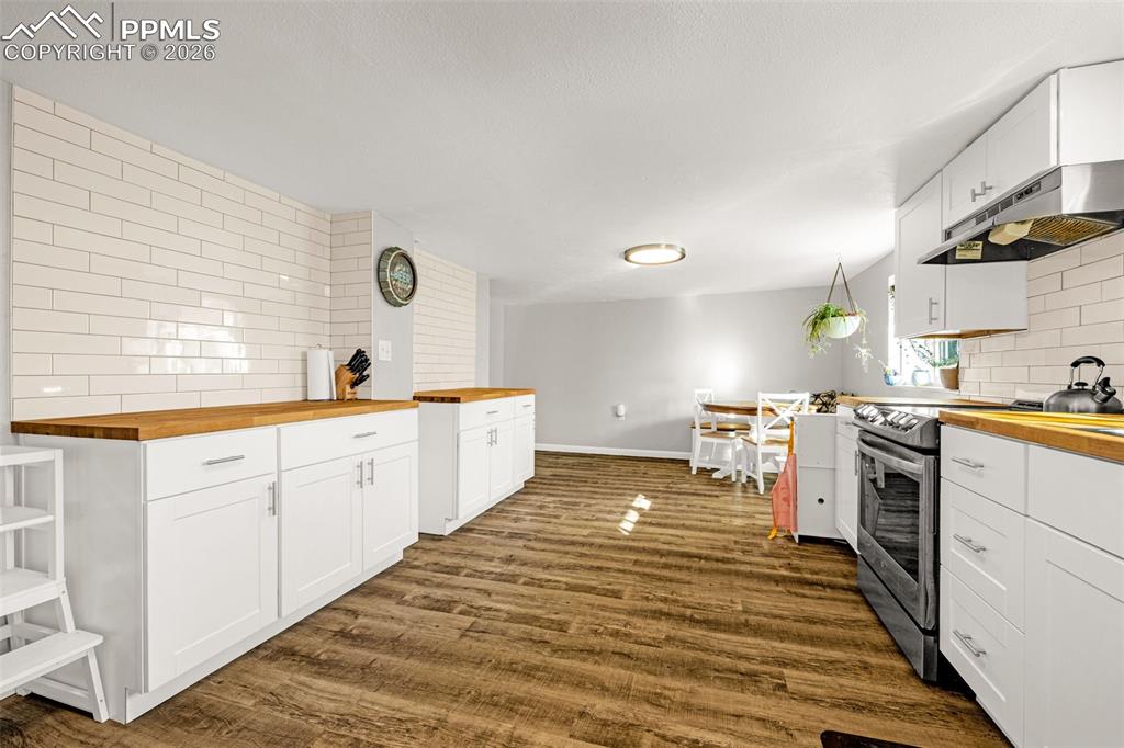 Image 9 of 38: Kitchen with wooden counters, tasteful backsplash, electric stove, and whit