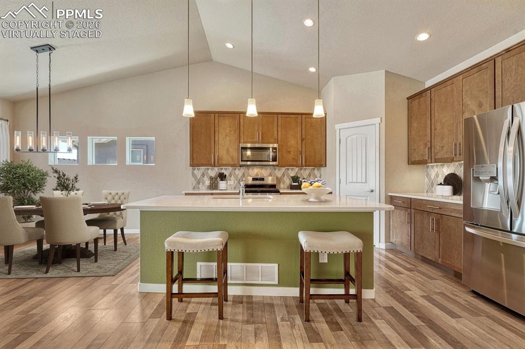 Image 3 of 50: Designer kitchen with island, pendant lights, quartz counters, stainless st