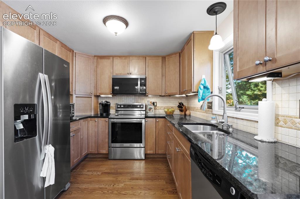 Image 10 of 43: Kitchen featuring wood-finish flooring, stainless steel appliances, dark co
